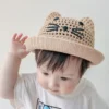 Un bébé porte un adorable petit chapeau bob sur fond clair