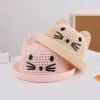 Deux petits chapeaux en forme de chaton pour bébés sont empilés sur une table claire