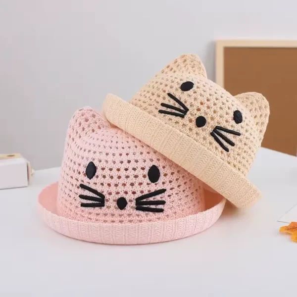 Deux petits chapeaux en forme de chaton pour bébés sont empilés sur une table claire