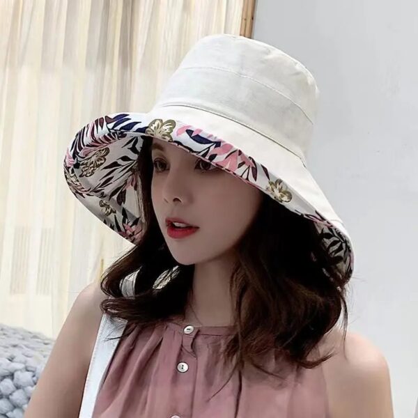 Une femme porte un bob chapeau élégant blanc sur un décor clair et lumineux