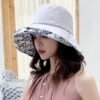 Une femme porte un bob chapeau élégant gris sur un décor clair et lumineux