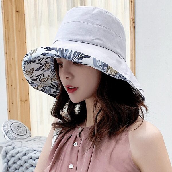 Une femme porte un bob chapeau élégant gris sur un décor clair et lumineux
