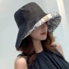 Une femme porte un bob chapeau élégant noir sur un décor clair et lumineux