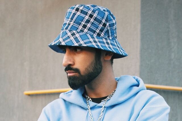 Un-jeune-homme-barbu-porte-un-bob-à-carreaux-bleu-et-blanc-sur la-tête