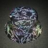 Une tête de mannequin en plastique, porésenteun chapeau bob avec des motifs réfléchissants en forme d'éclairs de foudre sur un tissu noir avec un arrière plant sombre
