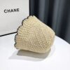 Un bob en paille couleur beige renversé sur le côté posé sur une table blanche