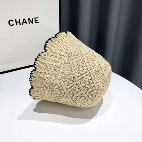 Un bob en paille couleur beige renversé sur le côté posé sur une table blanche
