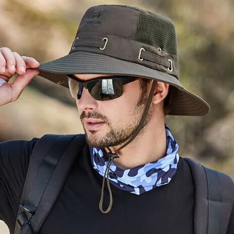Un homme de profil avec des lunettes noires de soleil porte un joli chapeau bob pêche couleur marron sur la tête sur un décor de nature flouté