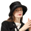 Une femme porte un bob en fourrure noir sur un fond blanc