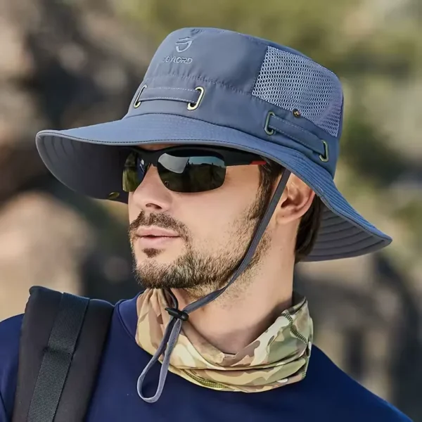 Un modèle de profil avec des lunettes noires de soleil porte un joli chapeau bob pêche couleur grise sur la tête sur un décor de nature flouté