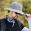 Un modèle de profil avec des lunettes noires de soleil porte un joli chapeau bob pêche gris clair sur la tête sur un décor de nature flouté