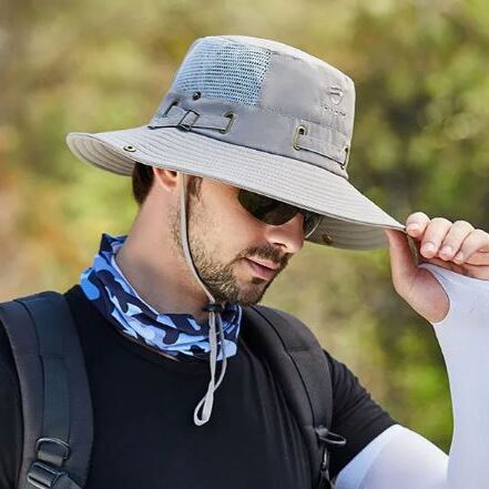 Un modèle de profil avec des lunettes noires de soleil porte un joli chapeau bob pêche gris clair sur la tête sur un décor de nature flouté