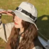 Une jeune femme porte un bob ficelle beige dans un décor de nature flouté