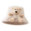 Un bob en fourrure beige avec une peluche d'ourson intégrée dessus
