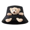 Un bob en fourrure noir avec une peluche d'ourson intégrée dessus