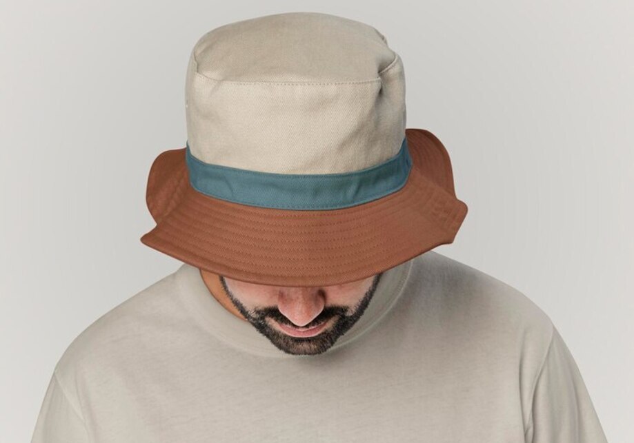 Homme prend la pose avec un bob chapeau élégant sur sa tête le fond de l'image est de couleur gris léger