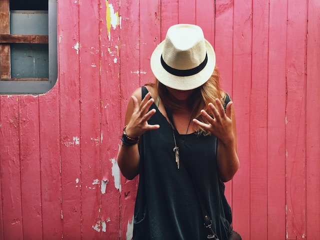 Femme prend la pause avec un chapeau fedora beige sur la tête