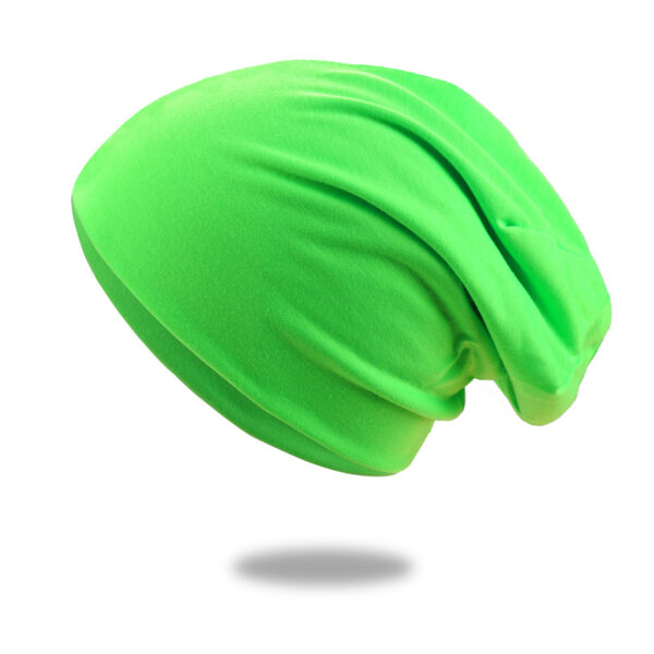 Un bonnet en coton vert pomme est montré sur un fond blanc