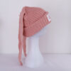 Le bonnet avec oreilles de lapin rose est présenté de profil sur sa tête de mannequin en plastique