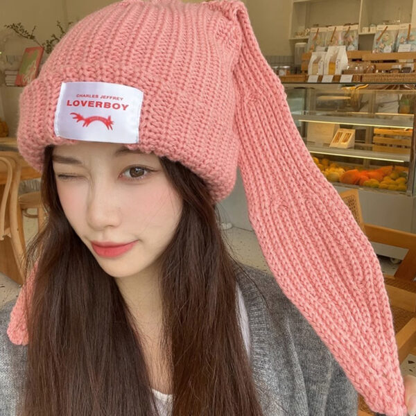 Une femme porte un bonnet lapin rose avec de longues oreilles
