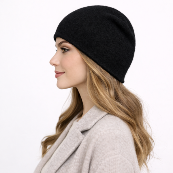 Une femme de profil porte un bonnet en cachemire noir sur un fond clair