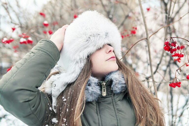 Femme dans un paysage enneigé et froid se protège avec un couvre chef en fourrure