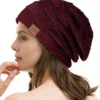 Une femme porte un bonnet bordeaux sur un décor blanc