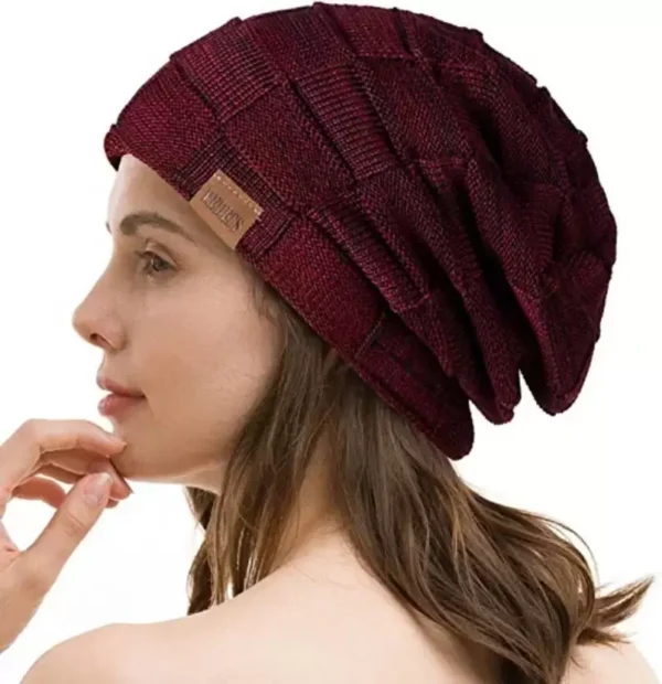 Une femme porte un bonnet bordeaux sur un décor blanc