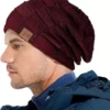 Un homme porte un bonnet bordeaux sur un décor blanc