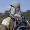 Un homme style aventurier de dos porte un bob randonnée avec une extension de protection pour la nuque sur un décor de nature