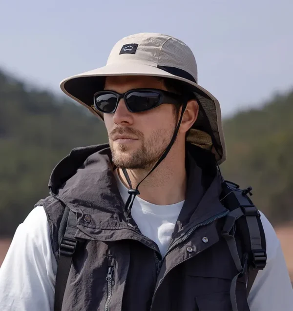 Un homme style aventurier porte un bob randonnée et des lunettes de soleil sur un décor de nature