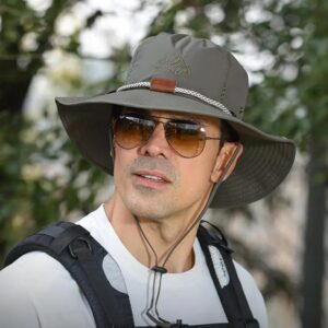 Un homme style explorateur porte un chapeau aventurier avec des grosses lunettes dans un décor de nature
