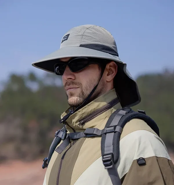 Un homme style aventurier porte un bob randonnée et des lunettes de soleil sur un décor de nature