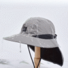 Un chapeau d'aventurier sur un présentoir est arrosé d'eau pour montrer qu'il est imperméable, l'eau ruisselle sur le chapeau bob sans y pénétrer
