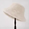 Un bob en fourrure pour les femmes couleur beige présenté sur un porte-chapeau