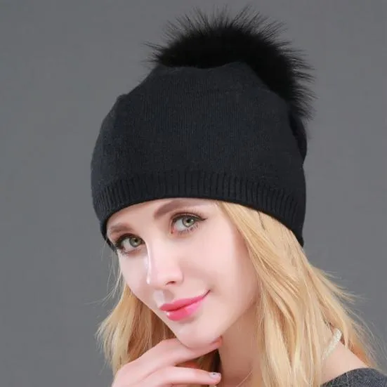 Modèle porte un bonnet noir à pompons pour femme sur fond gris foncé