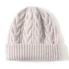 Bonnet en laine torsadée couleur écru pour femme, avec large revers et maille épaisse pour l’hiver.