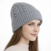 Bonnet d’hiver pour femme en laine grise, présenté en vue trois-quarts, avec tricot torsadé.